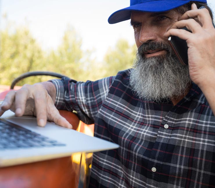 Ag producer on his phone and laptop 