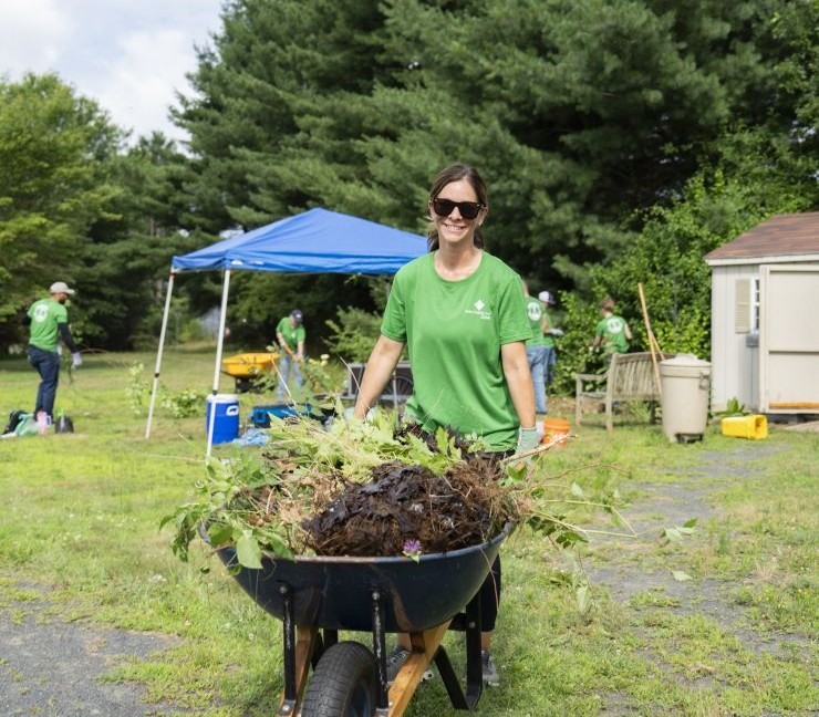 Farm Credit East staff member pushing a wheelbarrow and doing community service