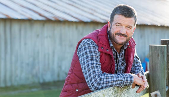 Northeastern farmer leaning on a fence post