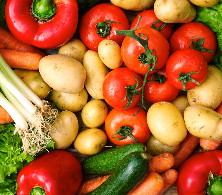 Collection of bright and fresh vegetables, including tomatoes, peppers, green onions, potatoes, carrots and more