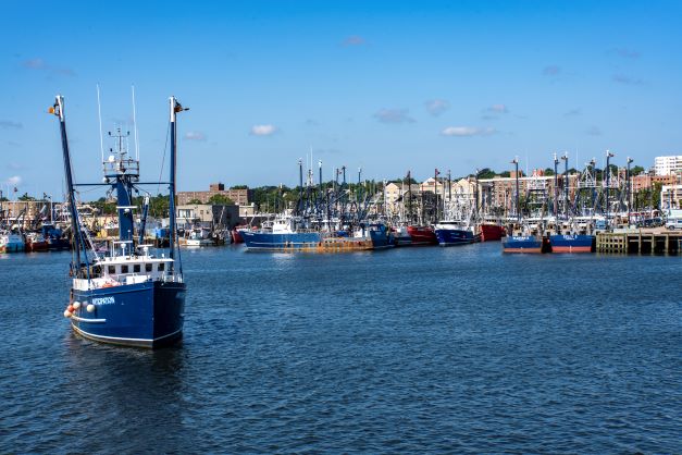 Pier 3 on the New Bedford, MA waterfront, large commercial fishing vessels in the foreground, New Bedford Whaling National Historic Park district and downtown in the background