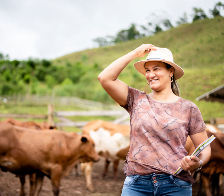 Woman rancher holding a notebook while standing in pen with cows