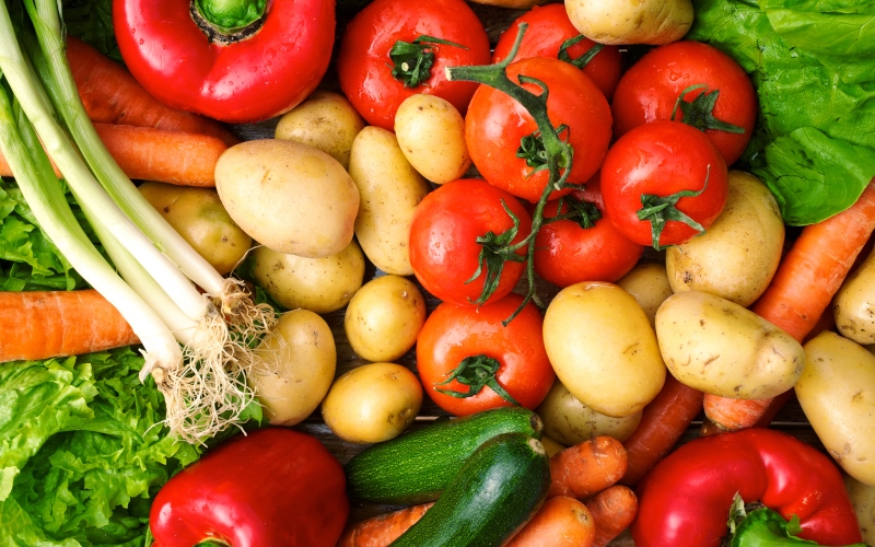 Grouping of different vegetables, green onions, tomatoes, red peppers, cucumbers, carrots, potatoes