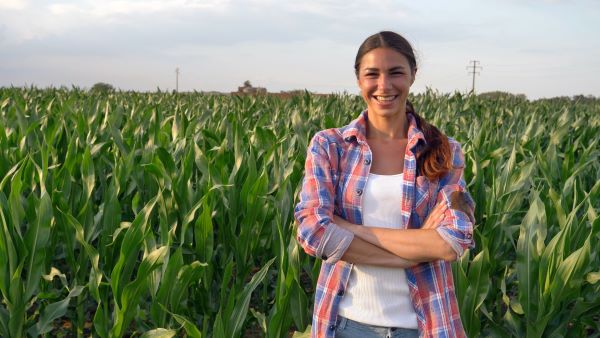 Young woman farmer standing in cornfield