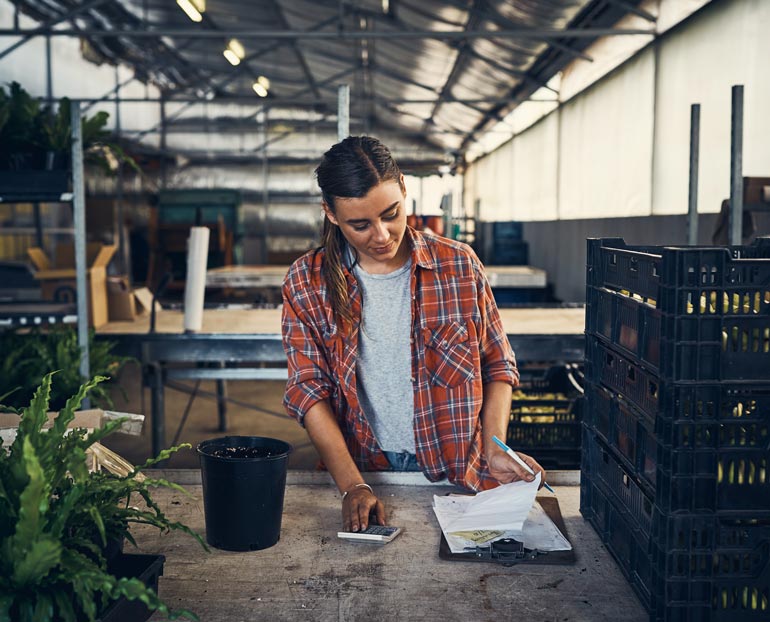 Greenhouse grower reviewing her financial records with a calculator