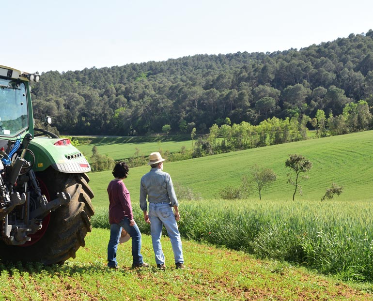 Agriculture couple and tractor overlooking their hillside farmland 