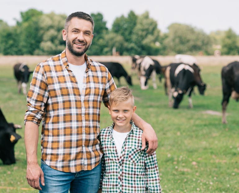 Ag father and son stand in front of dairy cows  