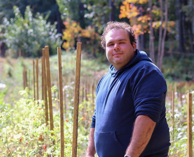 Young farmer standing in front of his rows of food crops