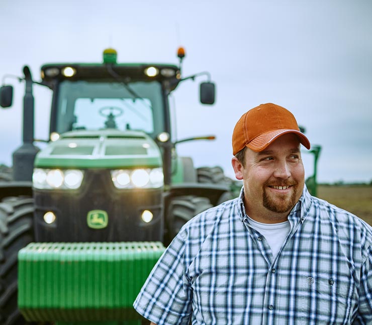 Smiling Farm Credit East customer in front of tractor after a hard day of planting 