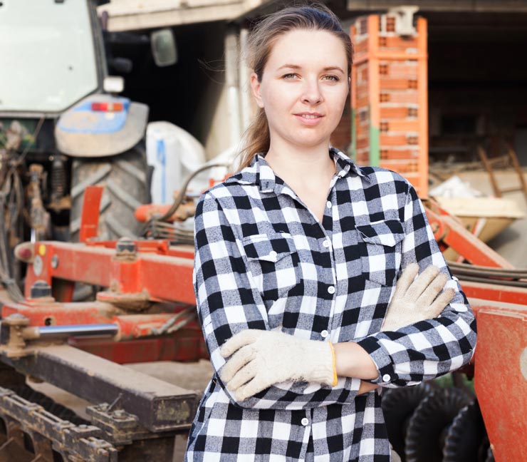  Ag woman leans against farm equipment  