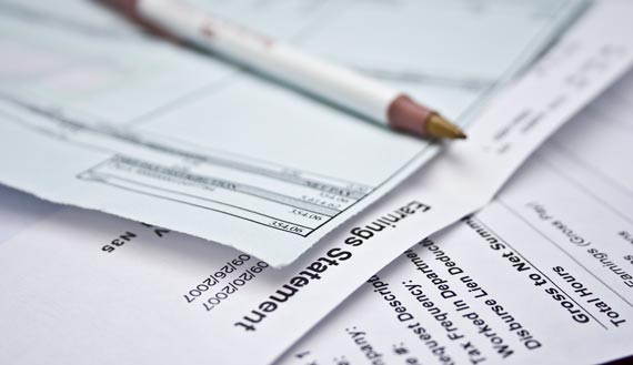 Close-up of payroll earnings statements and a pen 