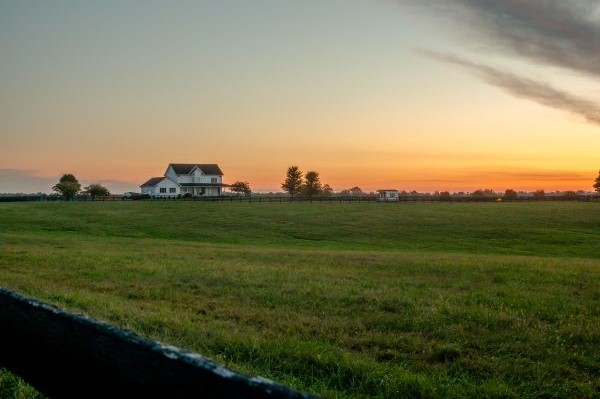 Rural home set back in agriculture pasture during sunset