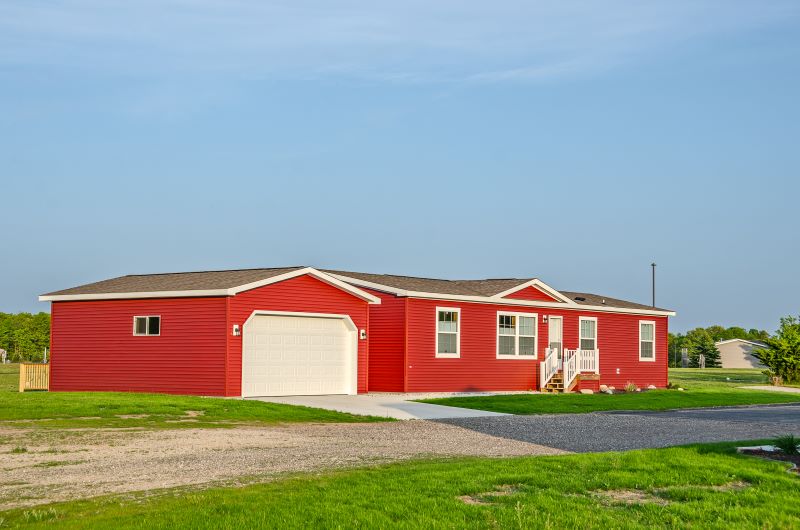 Manufactured home and garage with red vinyl siding in rural area