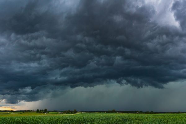 Supercell storm clouds with hail and rain over agriculture field