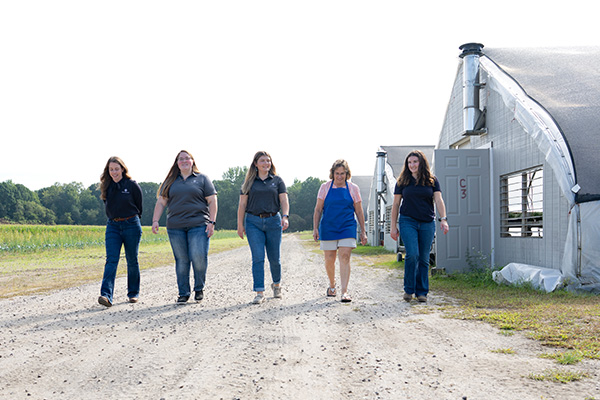 Five females walking alongside greenhouse