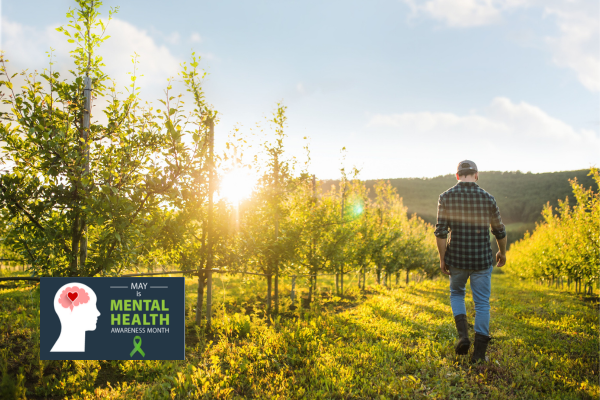 Young farmer walking away in a fruit orchard, Mental Health Awareness graphic logo is in the bottom left corner