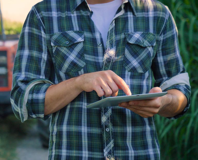 Close-up of farmer in field reviewing data on his tablet 