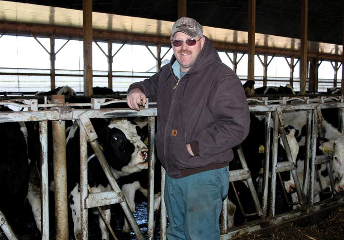 Stephen McKnight of River-Breeze Farm poses next to his herd of dairy cows 