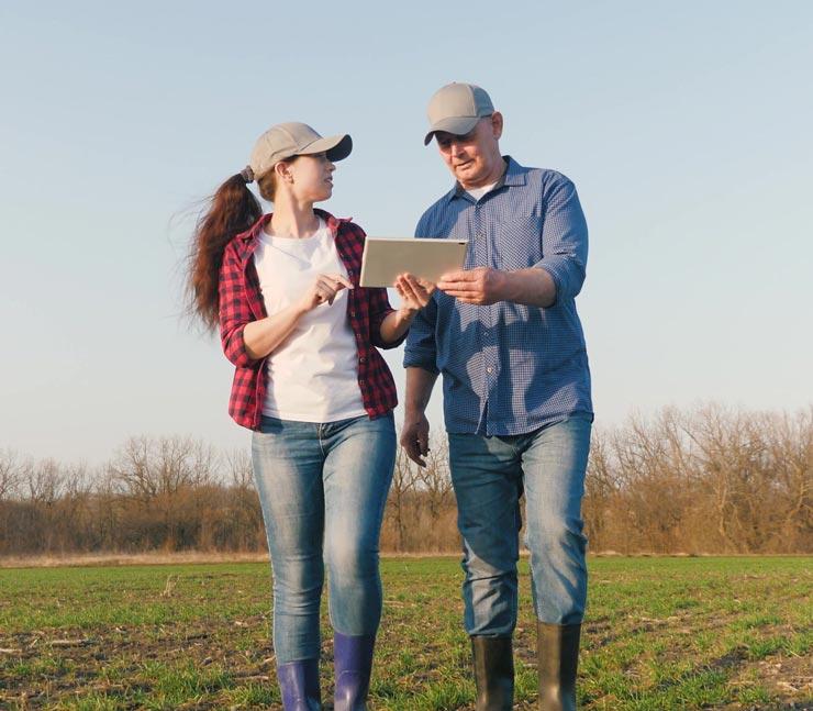 Man and woman look at tablet in field 